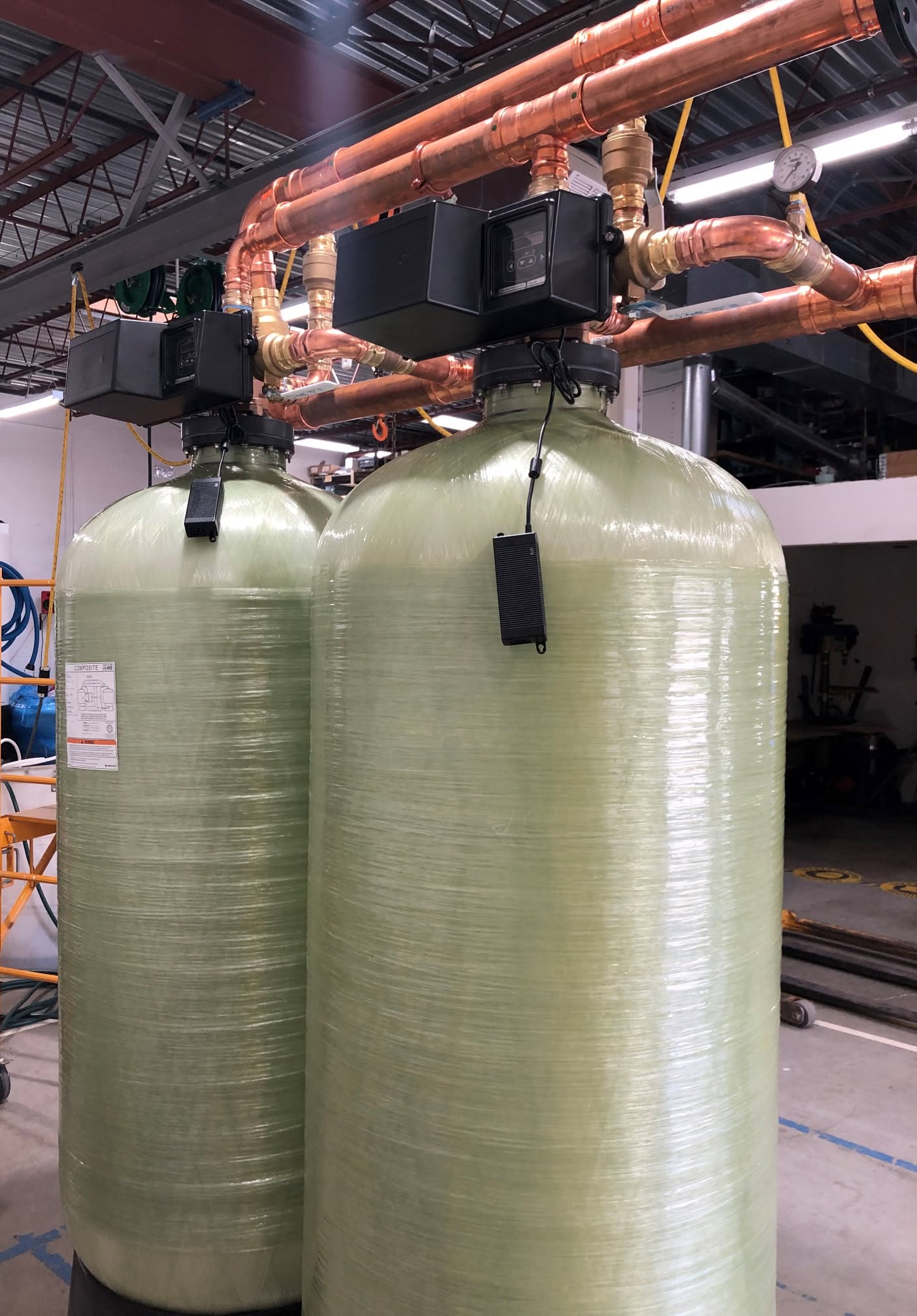 Two green fiberglass tanks with copper piping and digital controllers
