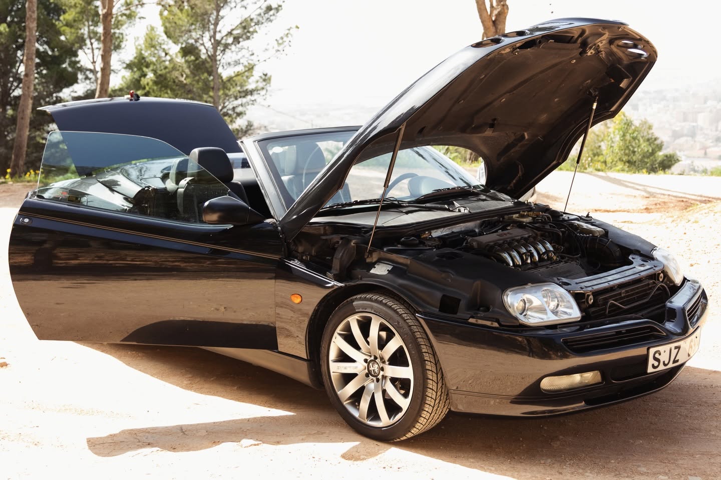 Black classic convertible with bonnet open showing engine bay