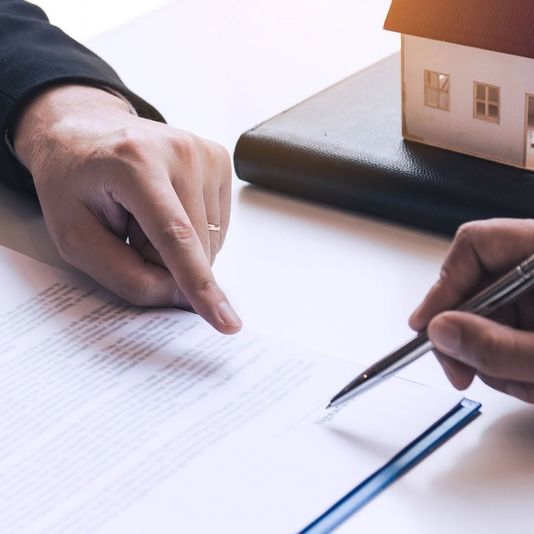 Document signing with house model, representing investment and property asset management