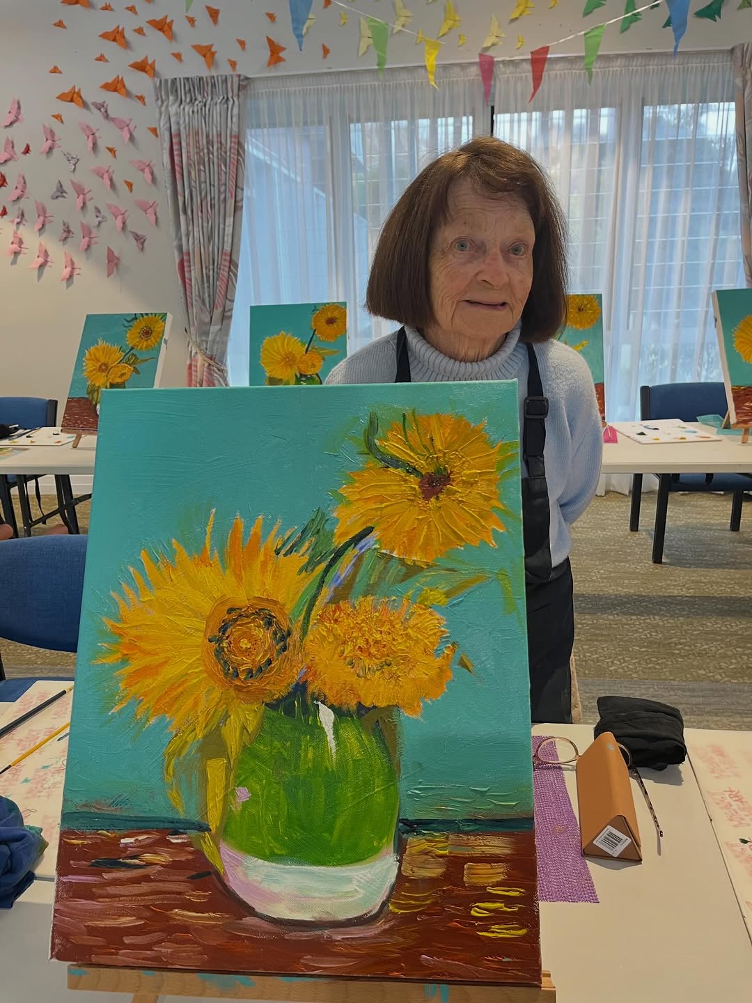 Senior resident proudly holding a Starry Night painting at an art session