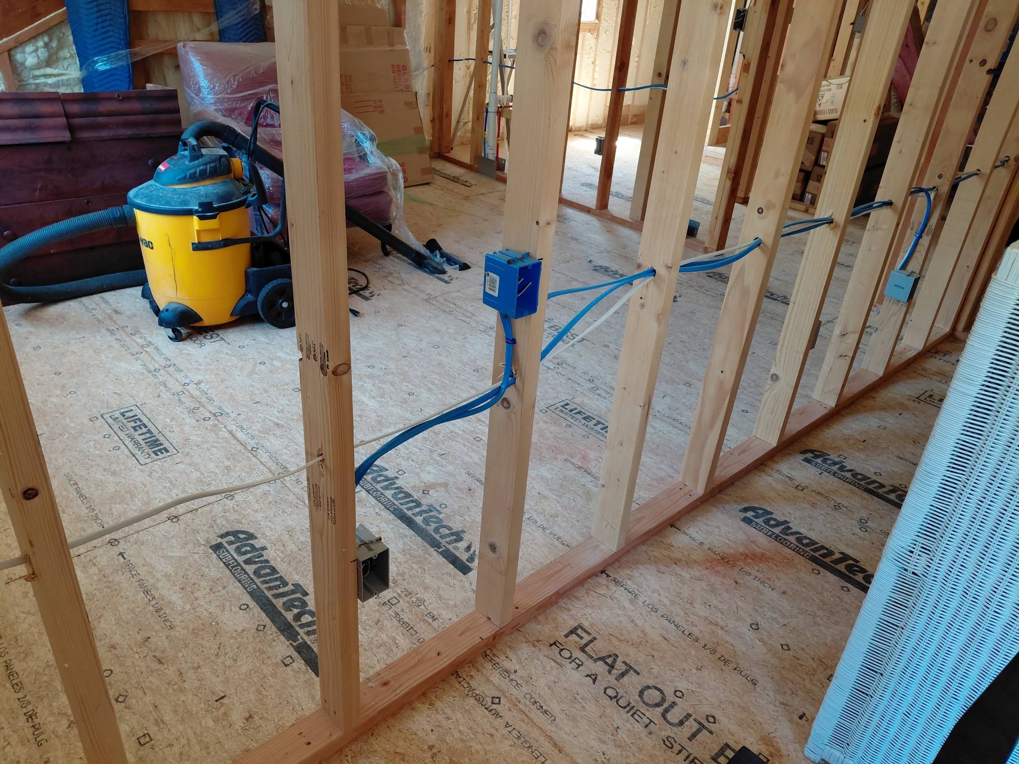 Framing wall with blue electrical wire runs and junction boxes during rough-in stage