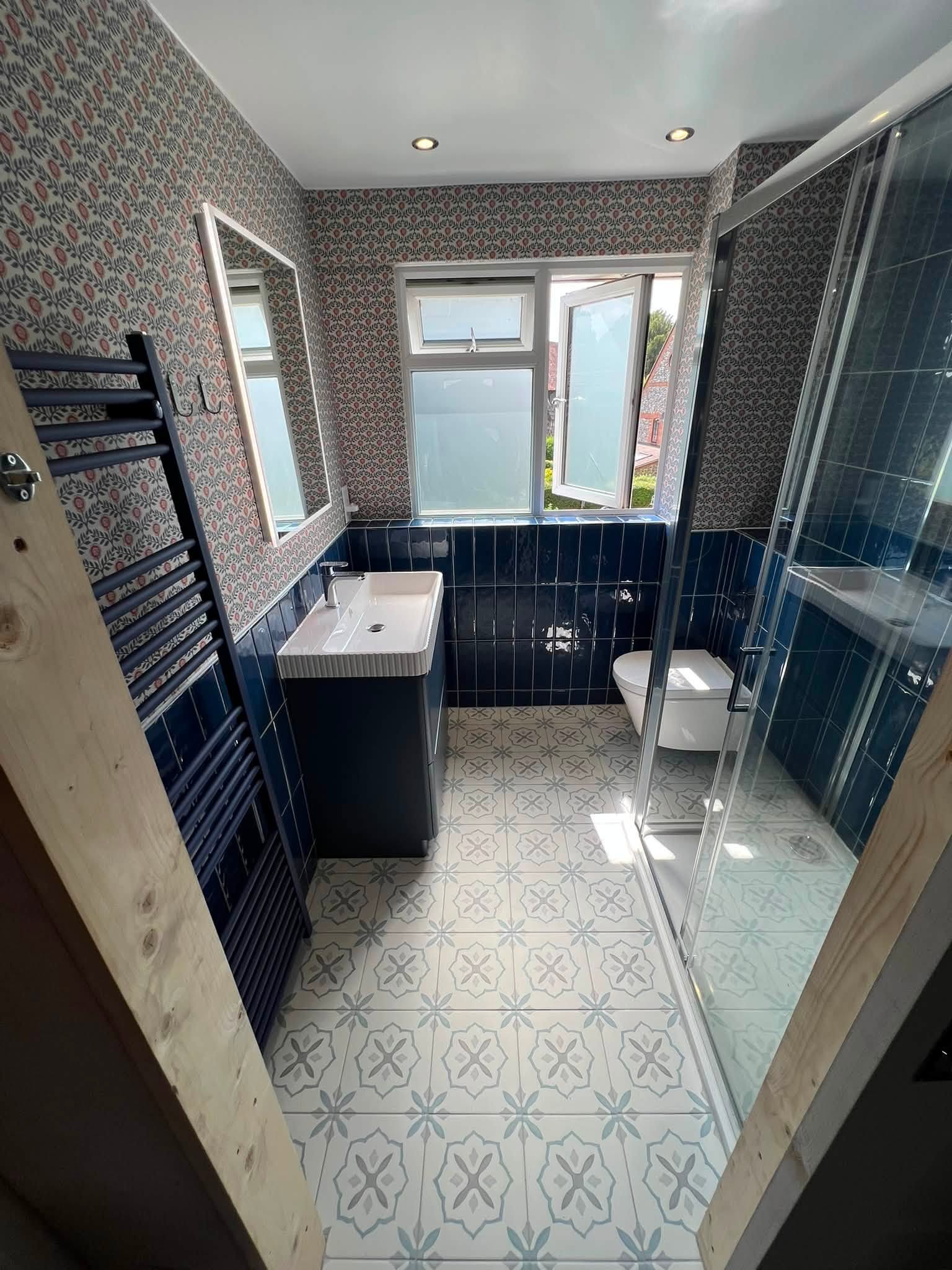 Completed bathroom renovation with blue tiles and patterned floor