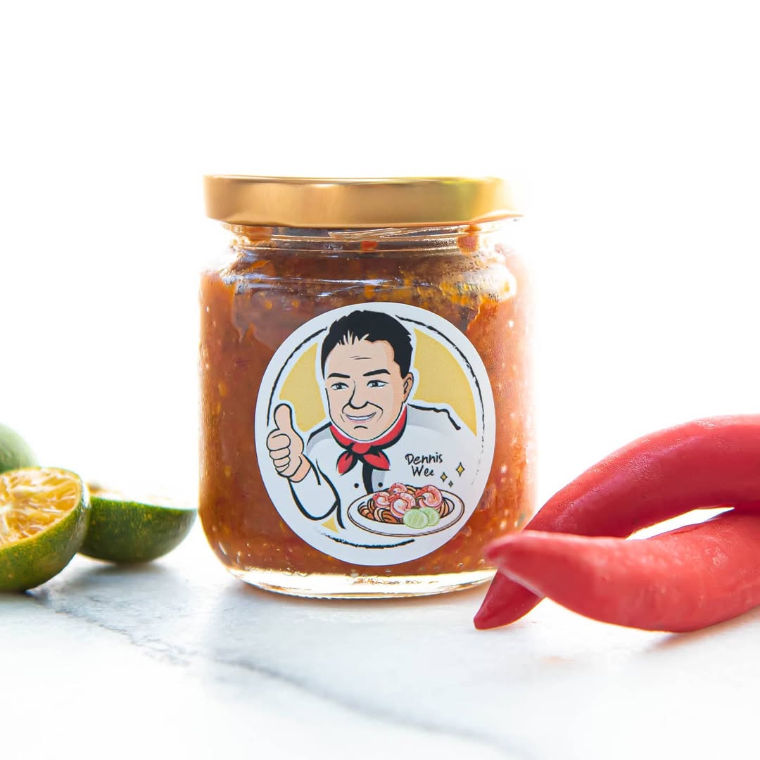 Dennis Wee branded sambal sauce jar with red chilli and calamansi on marble surface