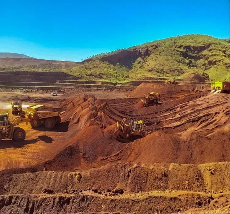 Iron ore open-cut mine with CAT haul trucks and excavators — earthmoving machinery operations