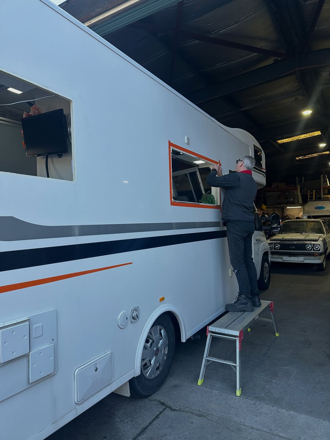 Technician carrying out a window repair on a caravan in the workshop