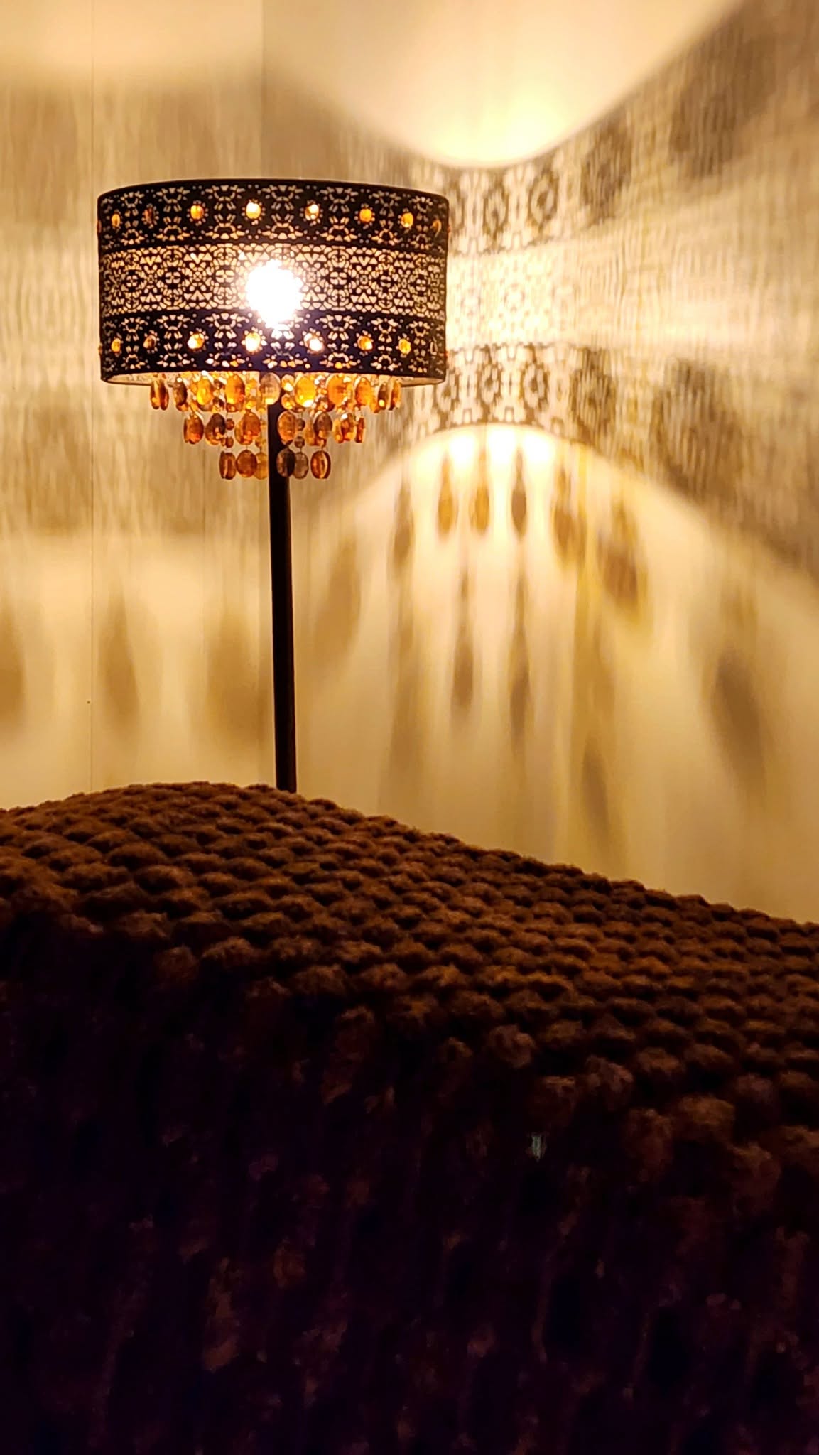 Warm, candlelit massage room with an ornate lamp casting a calming amber glow