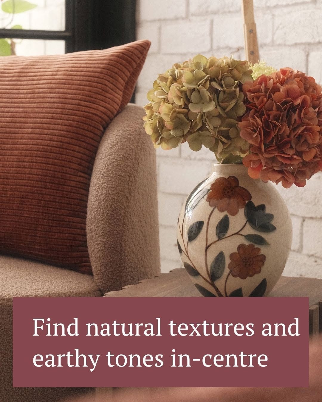 Decorative vase with hydrangeas and russet cushion on a sofa, representing Red Dollar's home decor range