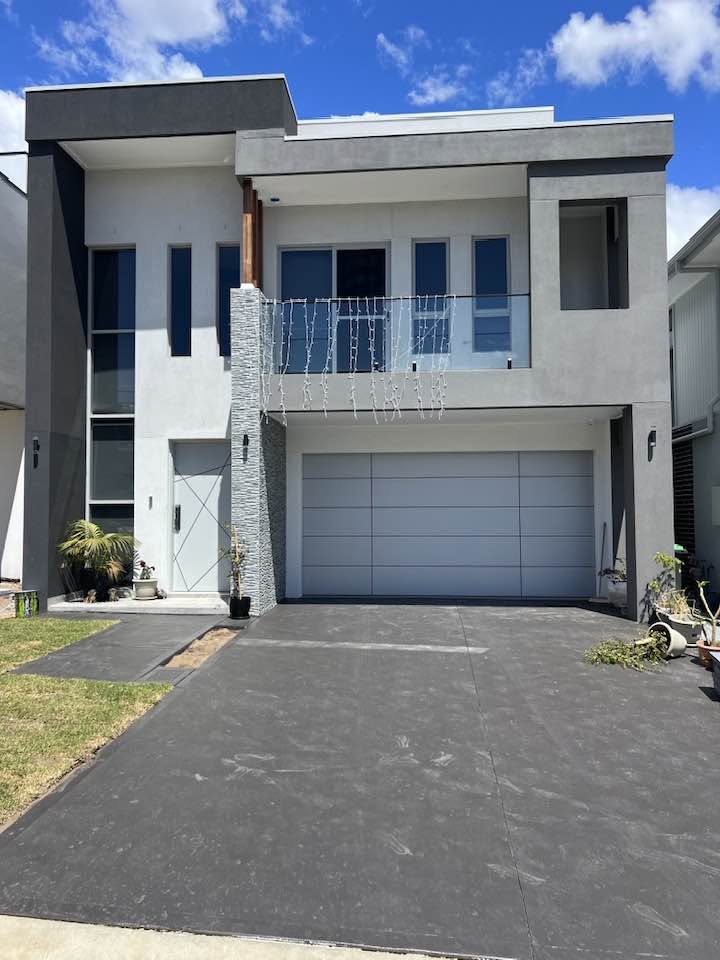 Grey rendered double-storey home with a stone feature wall, upper balcony and double garage