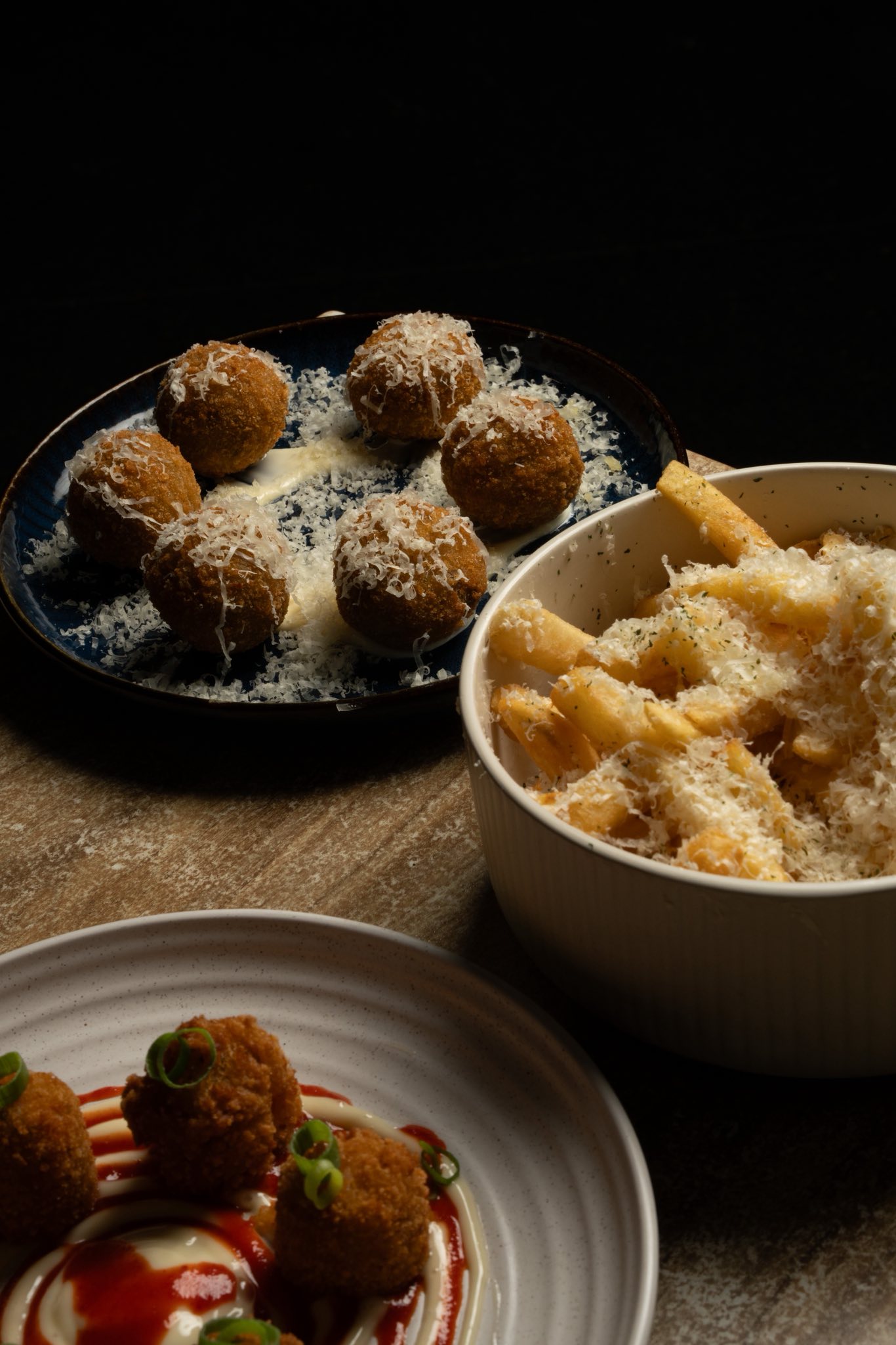 Arancini balls with parmesan and truffle fries in a bowl on dark background at Little Elm Cafe