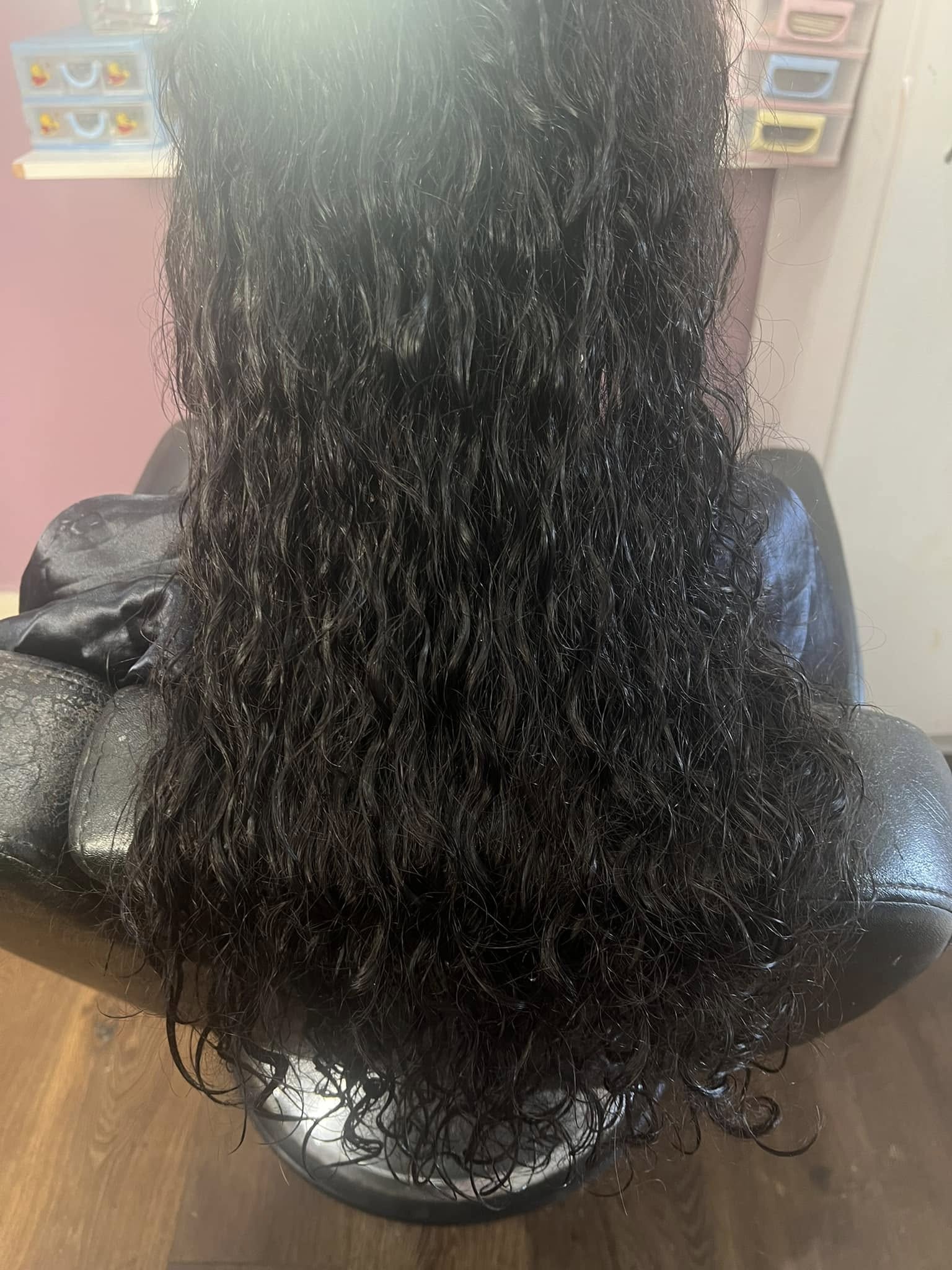 Long dark curly hair with a glossy finish in a salon chair