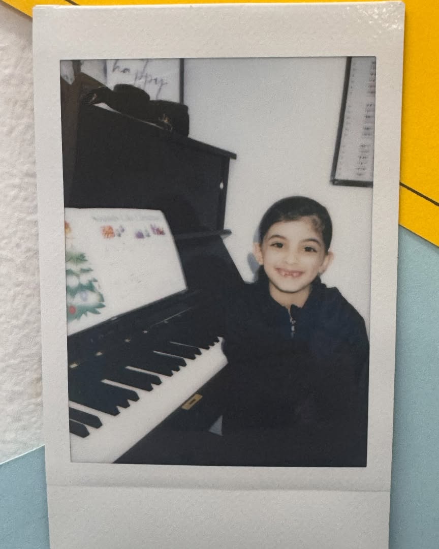 Smiling child sitting beside an upright piano