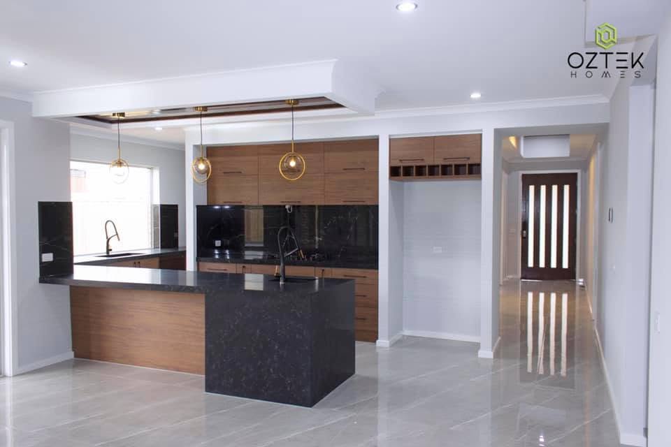 Luxury kitchen with walnut cabinetry, black marble island, and gold pendant lights