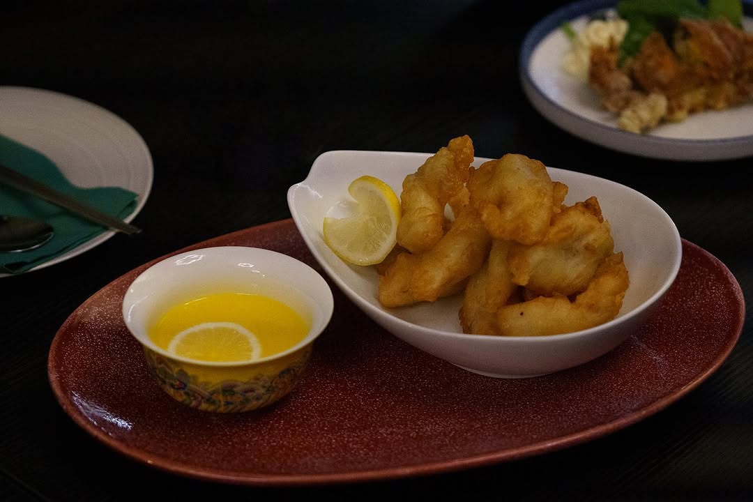 Battered fried seafood with lemon on a red ceramic plate