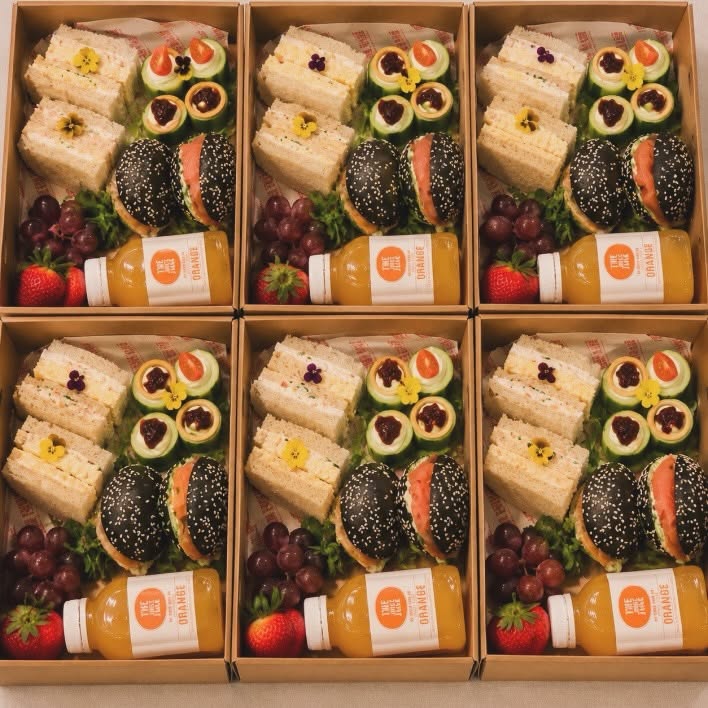 Corporate lunch boxes with gourmet sandwiches, fruit, and juice