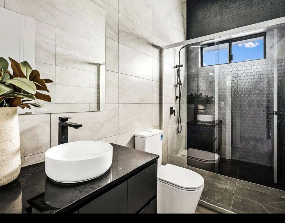 Modern bathroom with a black vanity, round basin and hexagon-tiled shower