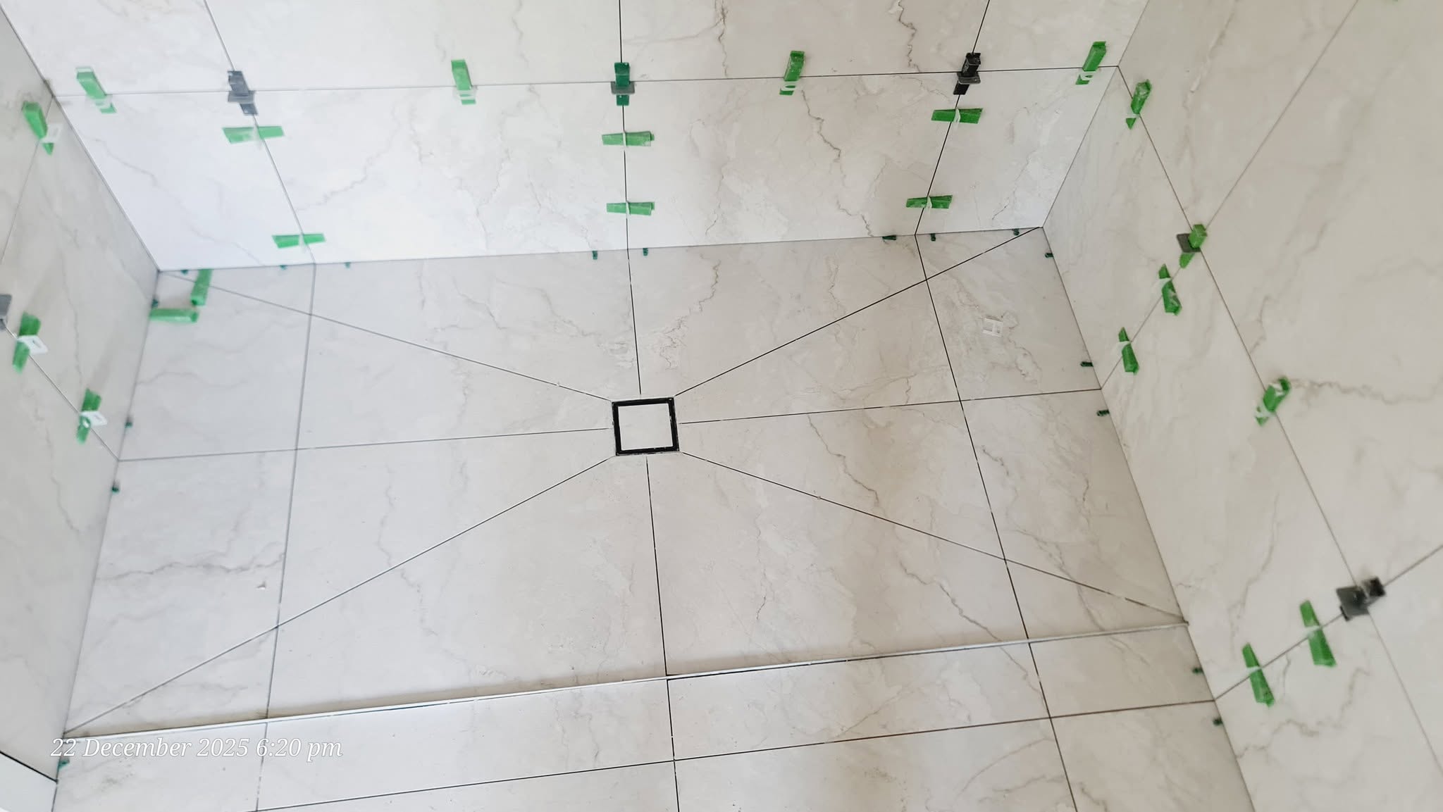 Overhead view of shower floor tiles in an elegant star-point pattern