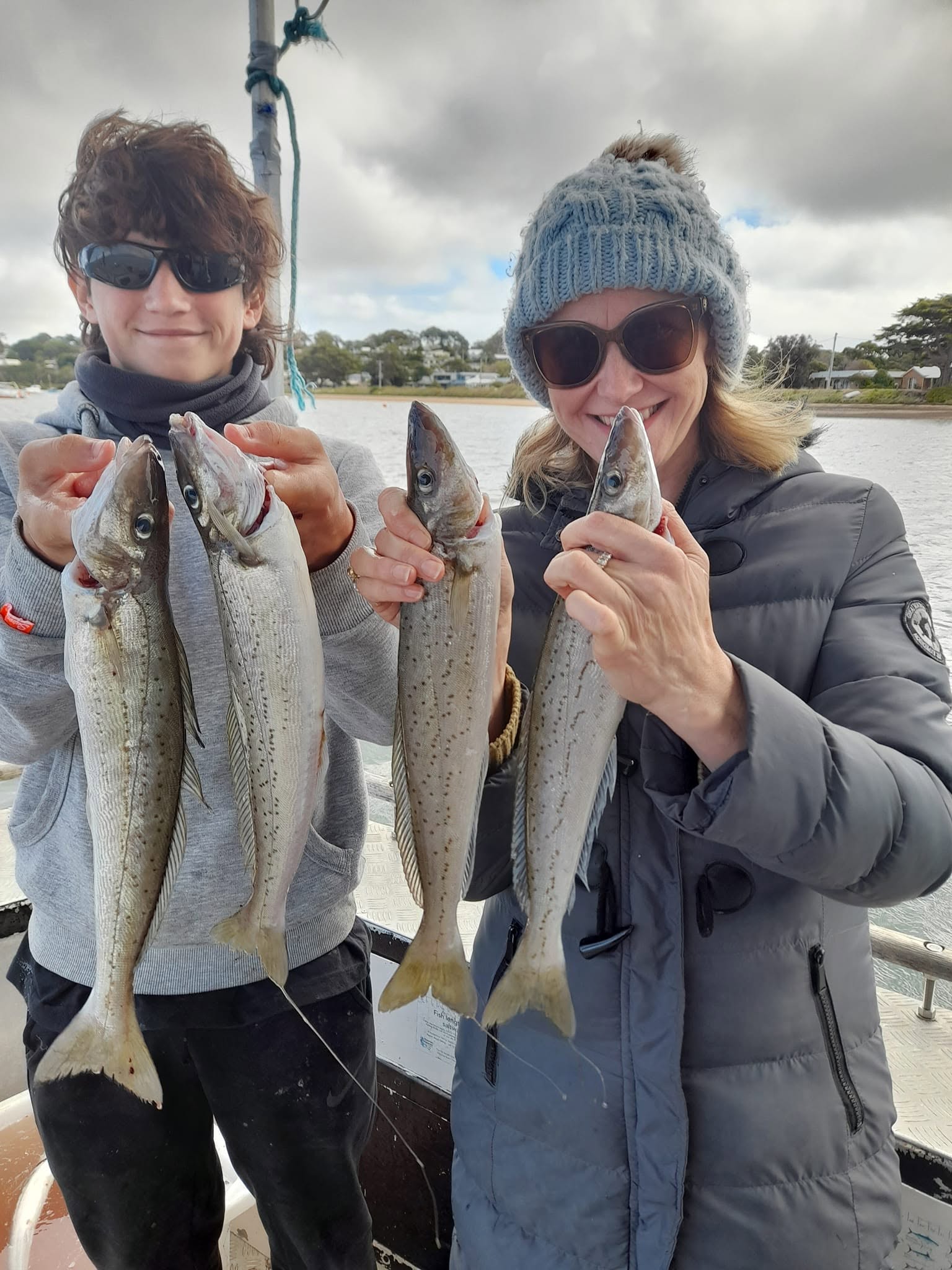 Two anglers on board showing off their catches of multiple King George whiting