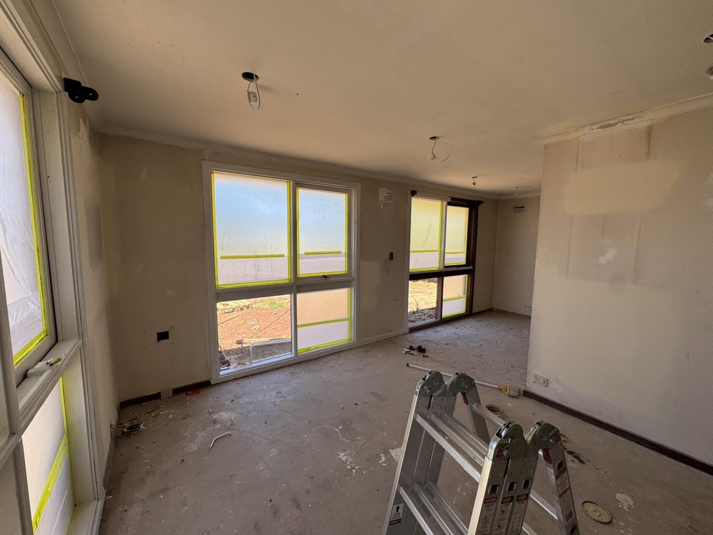 Interior room with windows masked with tape in preparation for painting