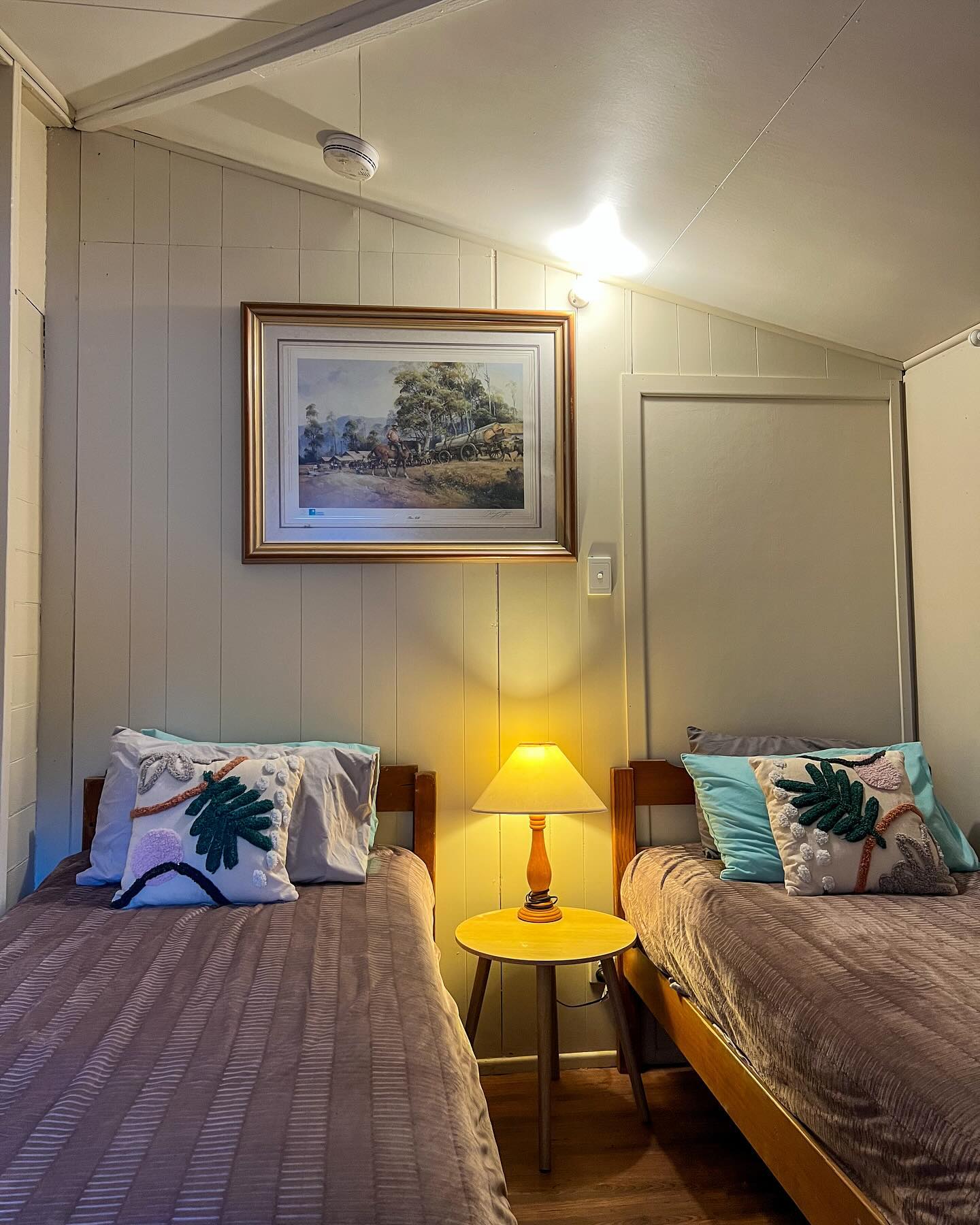 Cosy twin bedroom with warm lamp and country-style decor at the Yandaran Hotel