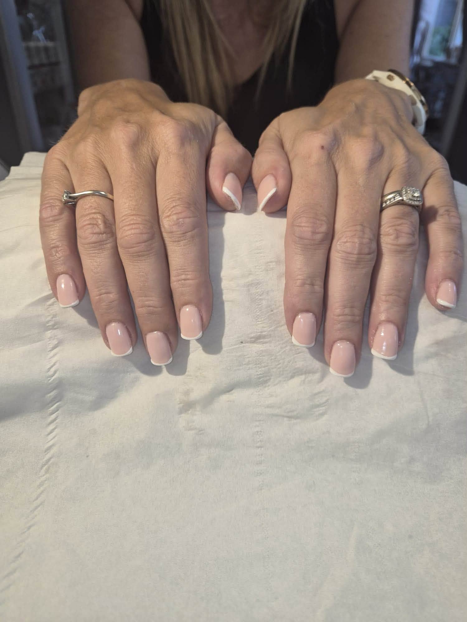 Beautifully manicured nails with soft pink french tips on white linen