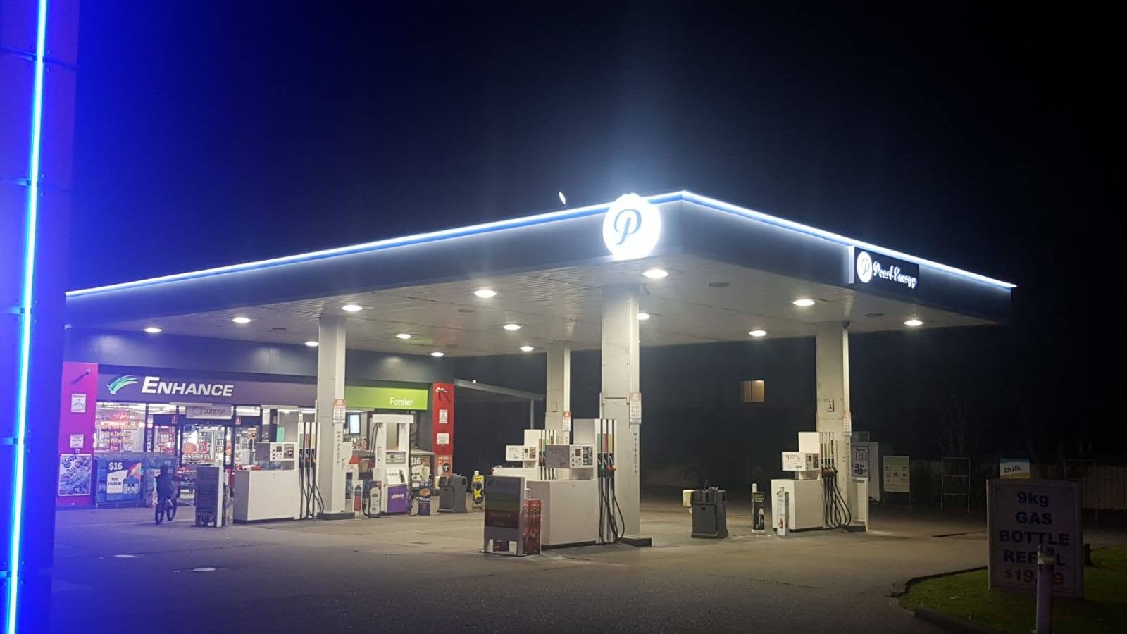 Pearl Energy station forecourt at night showing the well-lit canopy and service bays