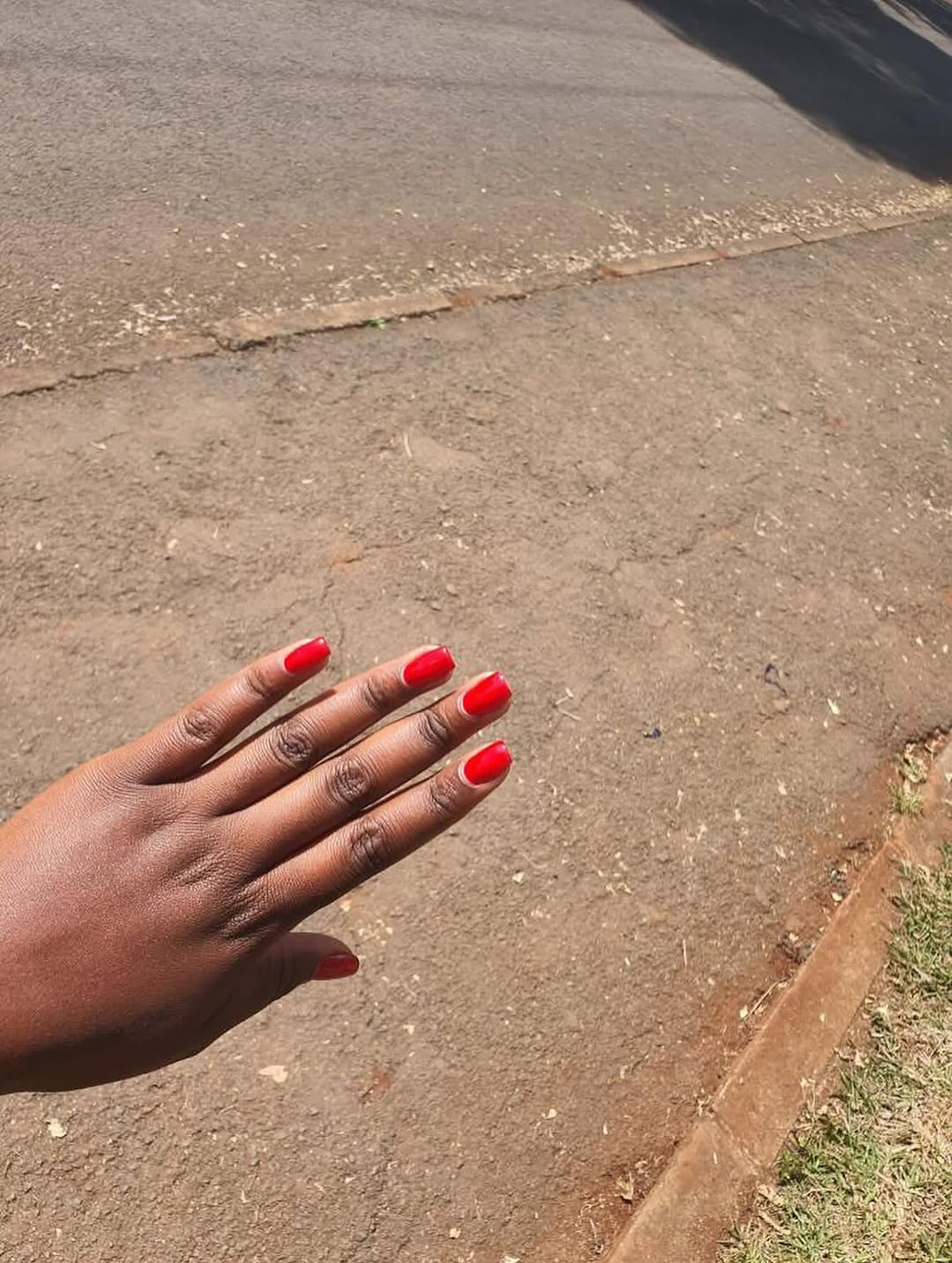 Bright red short nail polish on pavement