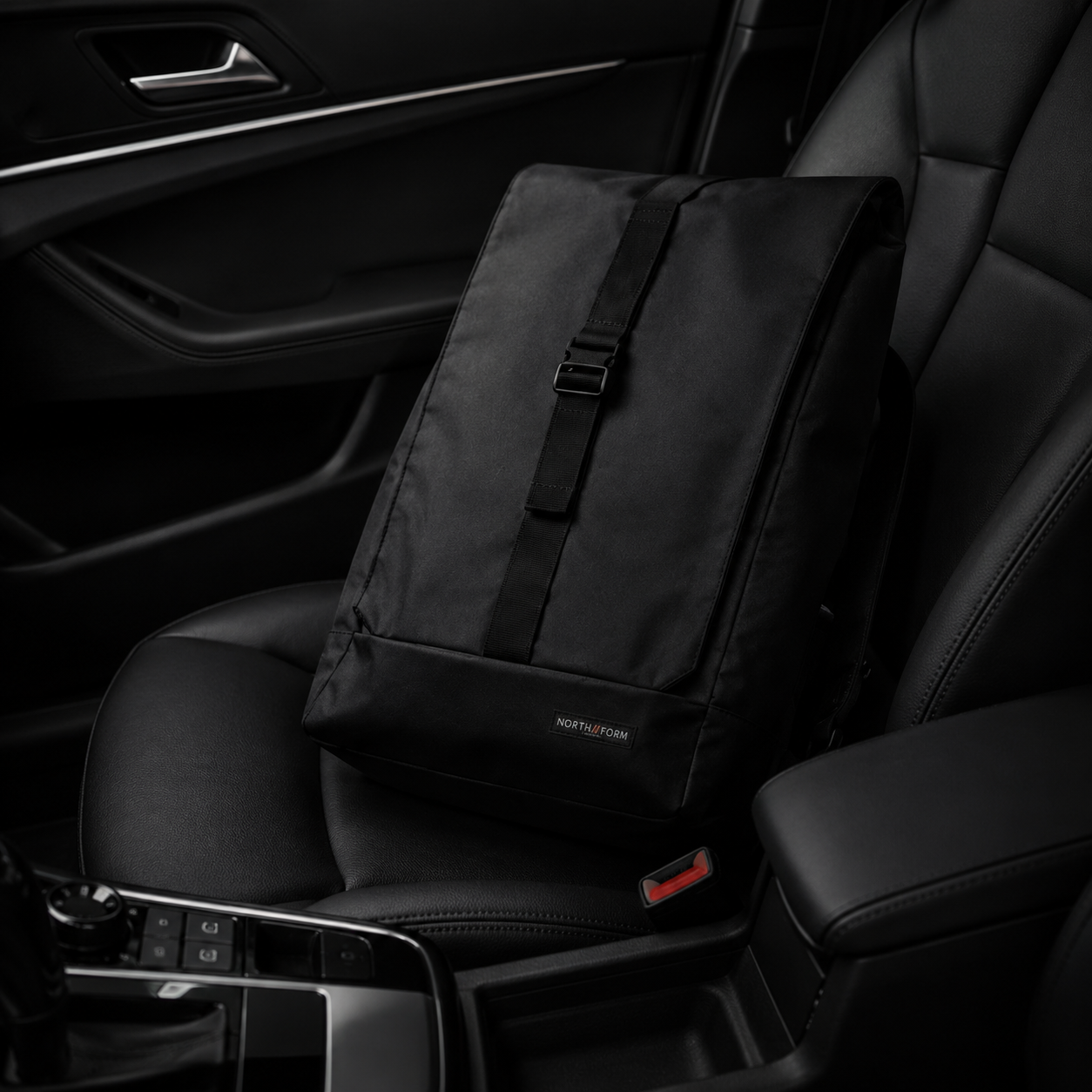 Black NORTH//FORM backpack resting on dark leather car seat interior