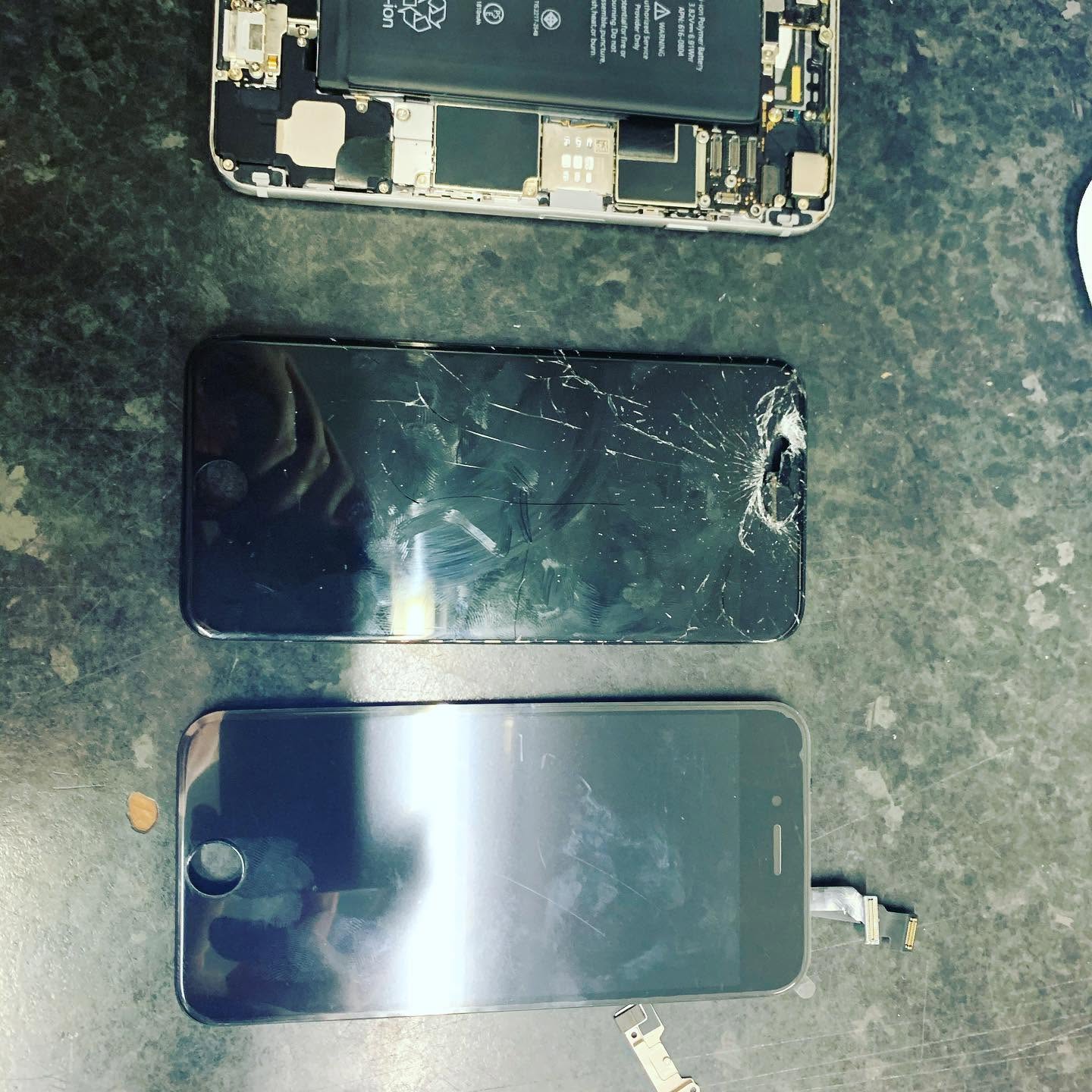 Smartphone internal components and cracked screen laid out for repair