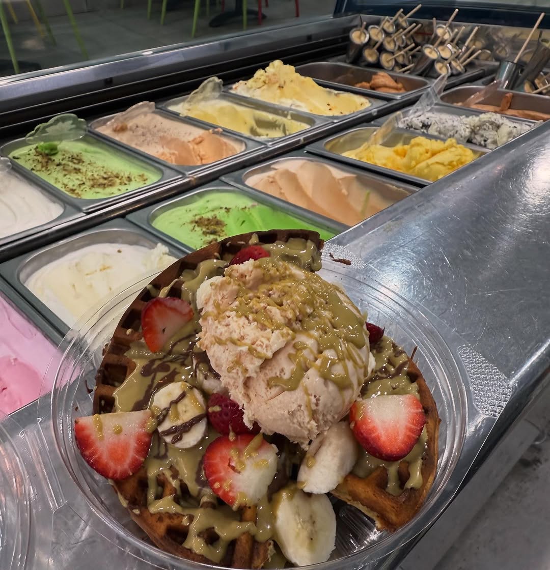 Ice cream display counter with colourful gelato tubs and a loaded waffle bowl