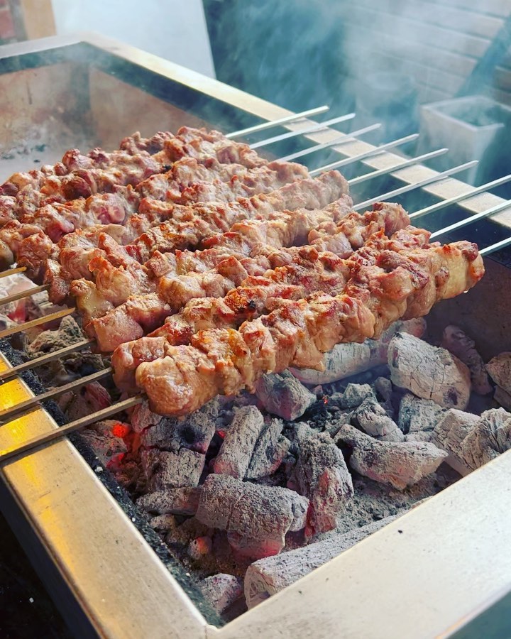 Marinated meat skewers cooking over glowing charcoal