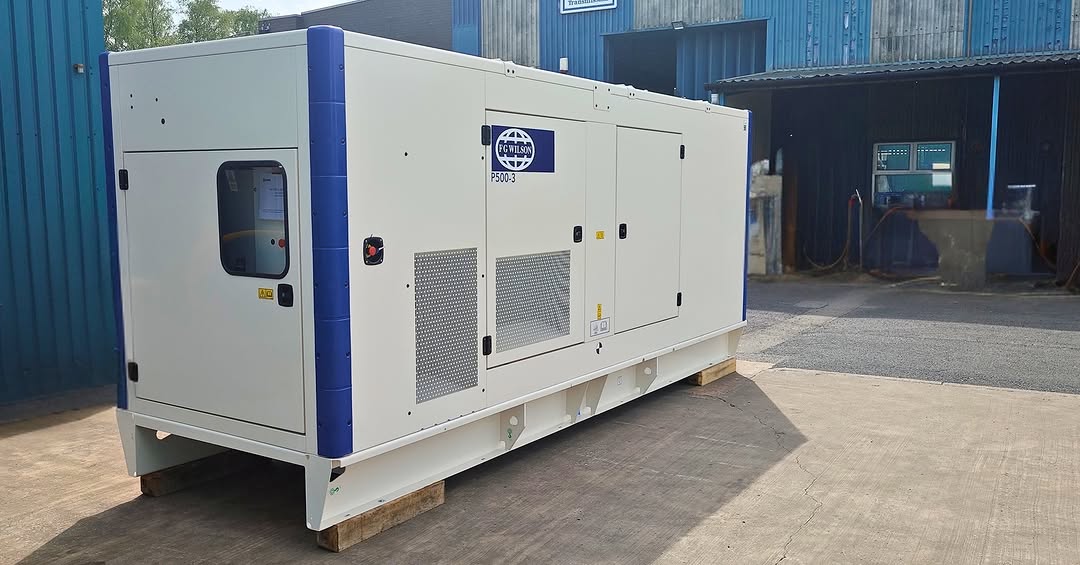 Large industrial power unit and agricultural equipment outside a workshop