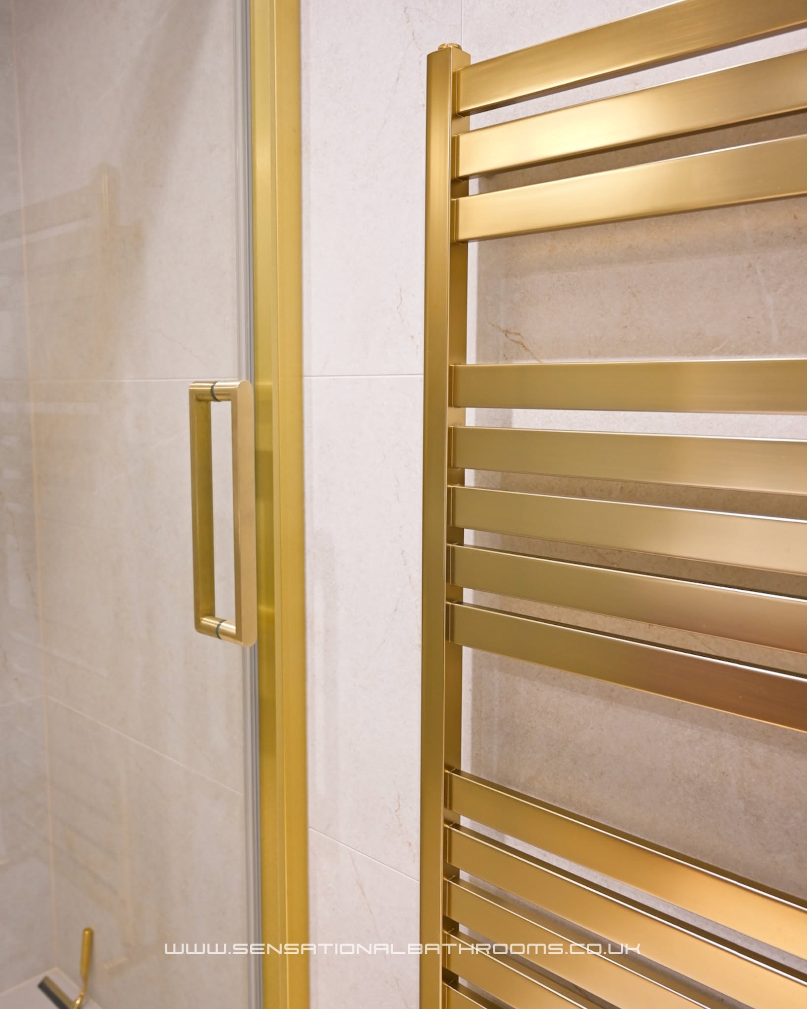 Elegant gold-framed shower enclosure with illuminated niche and brushed gold hand shower fitting
