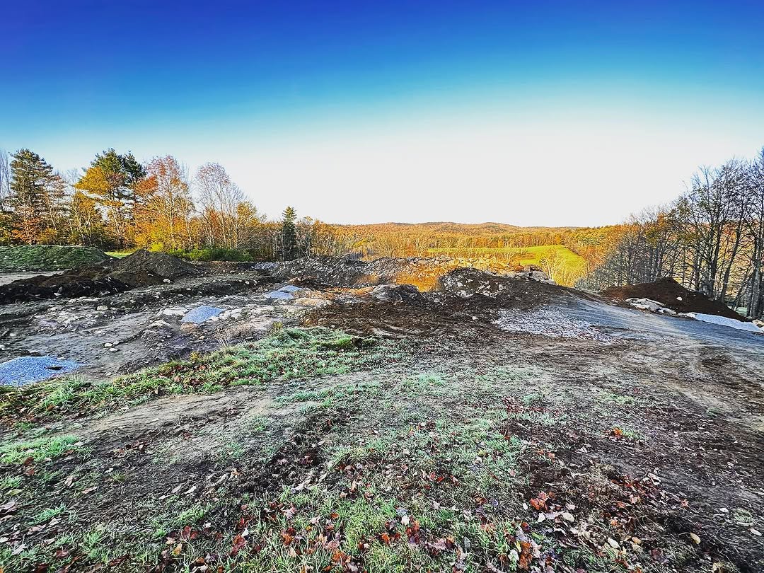 Construction site with autumn foliage and scenic countryside backdrop