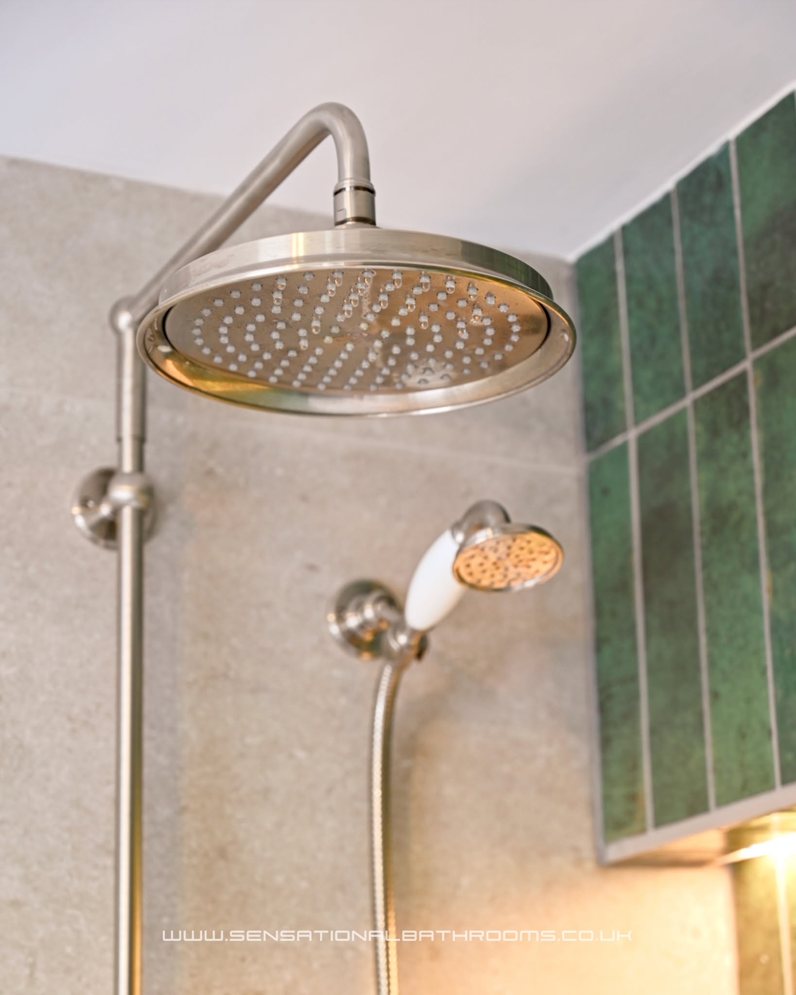 Brushed nickel rainfall showerhead and hand shower against stone and emerald green tiles