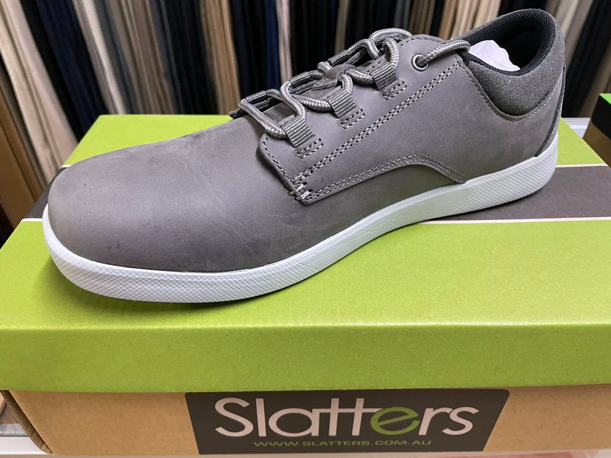 Grey leather casual shoe with a white sole on a shoe box