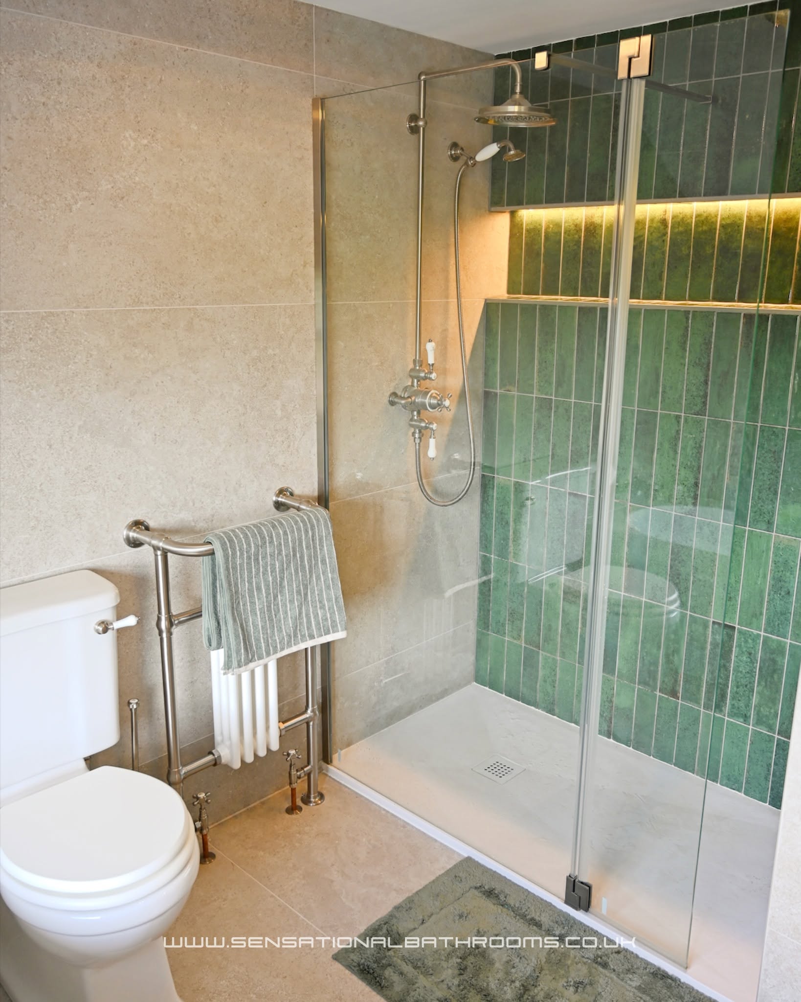 Completed bathroom renovation featuring a walk-in shower with green tiles, heritage towel radiator, and stone-look wall tiles