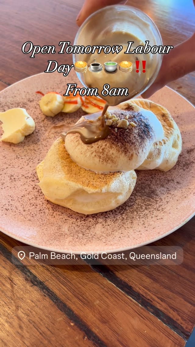 Stack of fluffy soufflé pancakes with cocoa powder and caramel sauce on a pink plate with fresh fruit