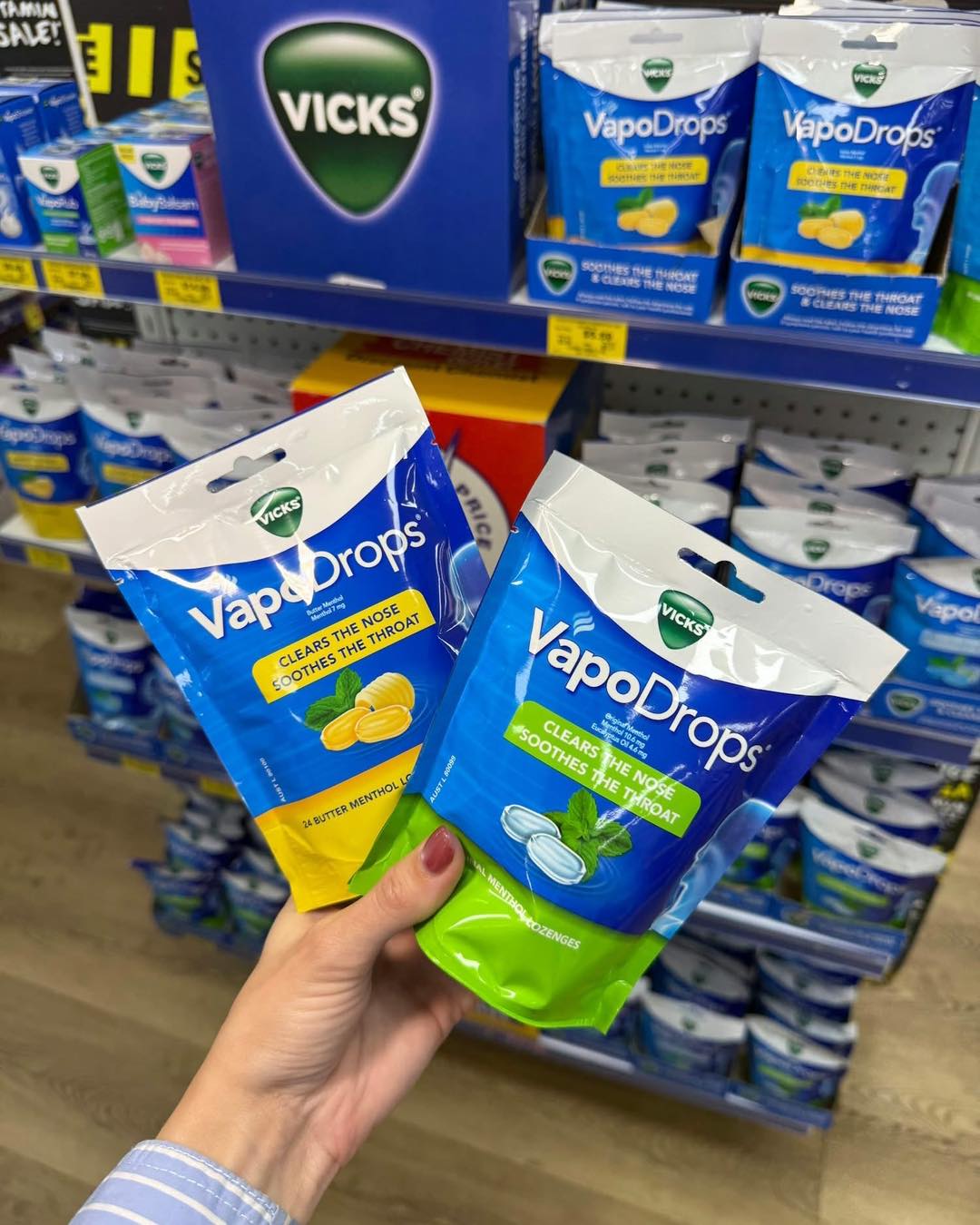 Two bags of Vicks VapoDrops lozenges held in front of a shelf display