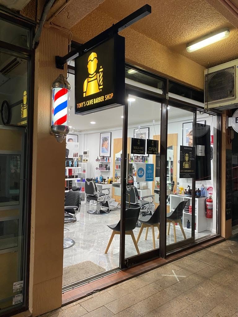 Tony's Cave Barber Shop interior at night — barber chairs and product shelves
