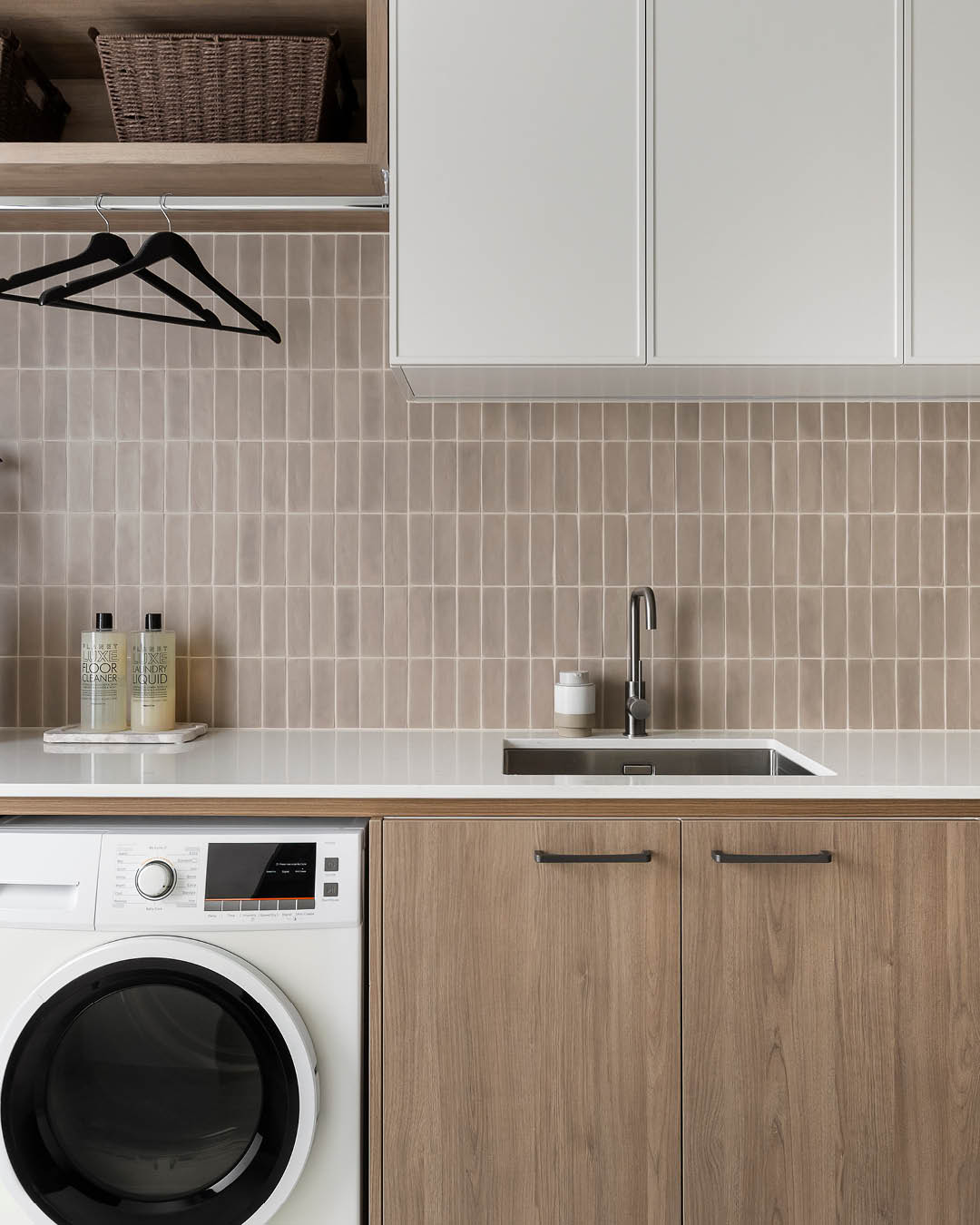 Laundry with tiled splashback and timber cabinetry in a Carlisle display home