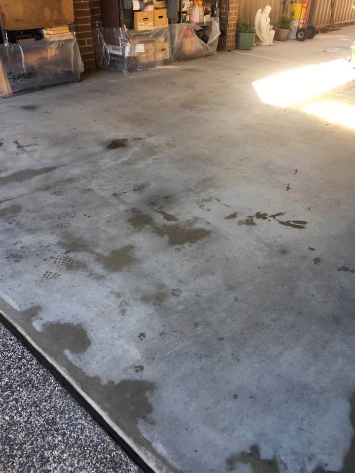 Concrete garage floor before pressure cleaning, showing built-up grime and stains