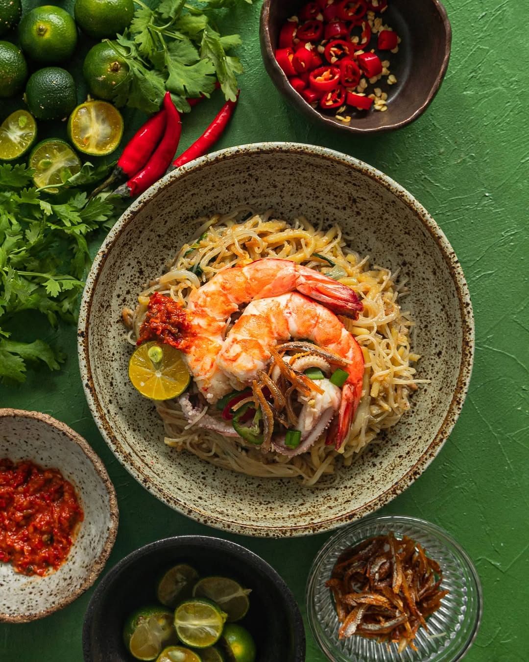 Bowl of Hokkien Mee with prawns and squid on a green background