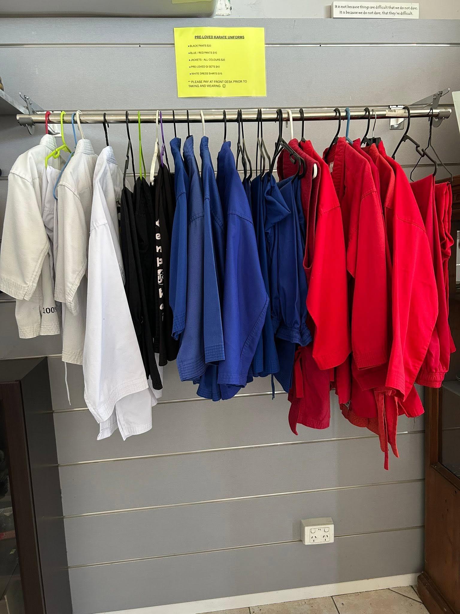 Rack of club karate uniforms in white, black, blue and red available at the dojo