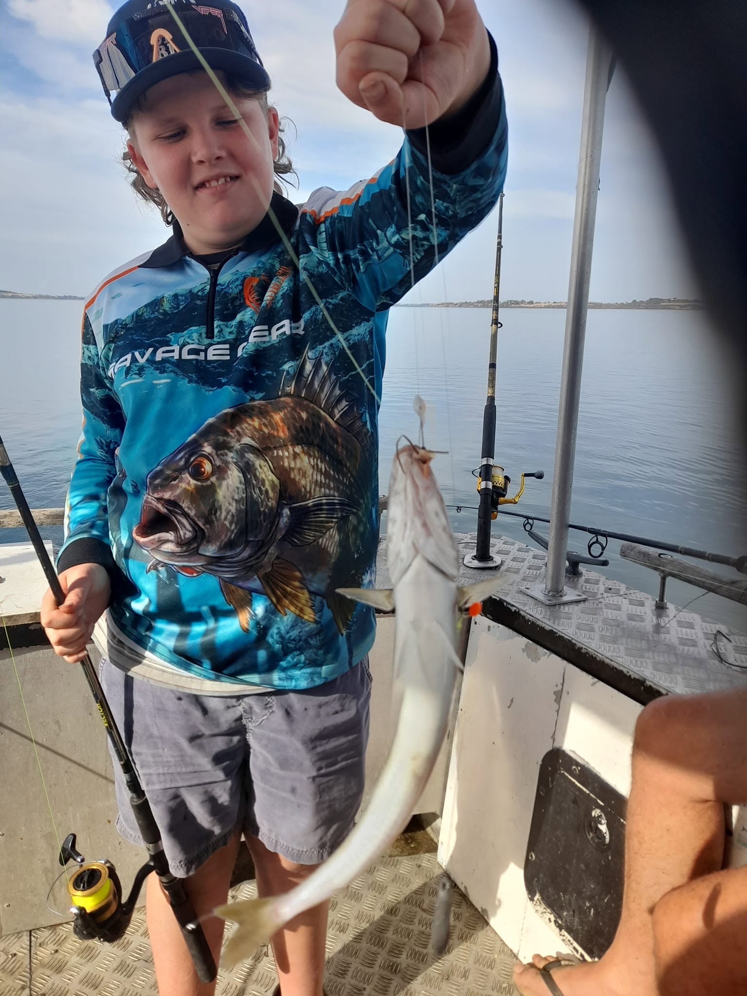 Young angler on the charter boat holding a flathead fish catch