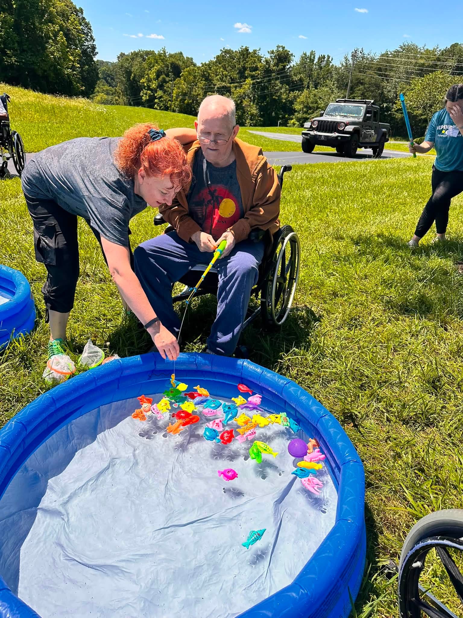Therapist assisting a resident with a fun fishing activity outdoors