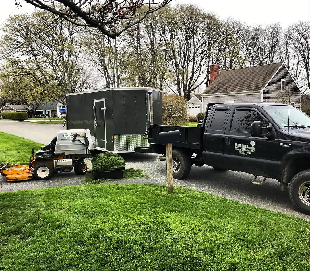 Property maintenance truck with trailer and lawn equipment — Primo Property Maintenance on-site