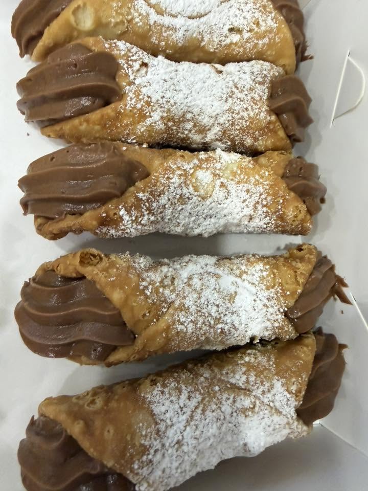 Classic ricotta cannoli dusted with icing sugar on parchment paper