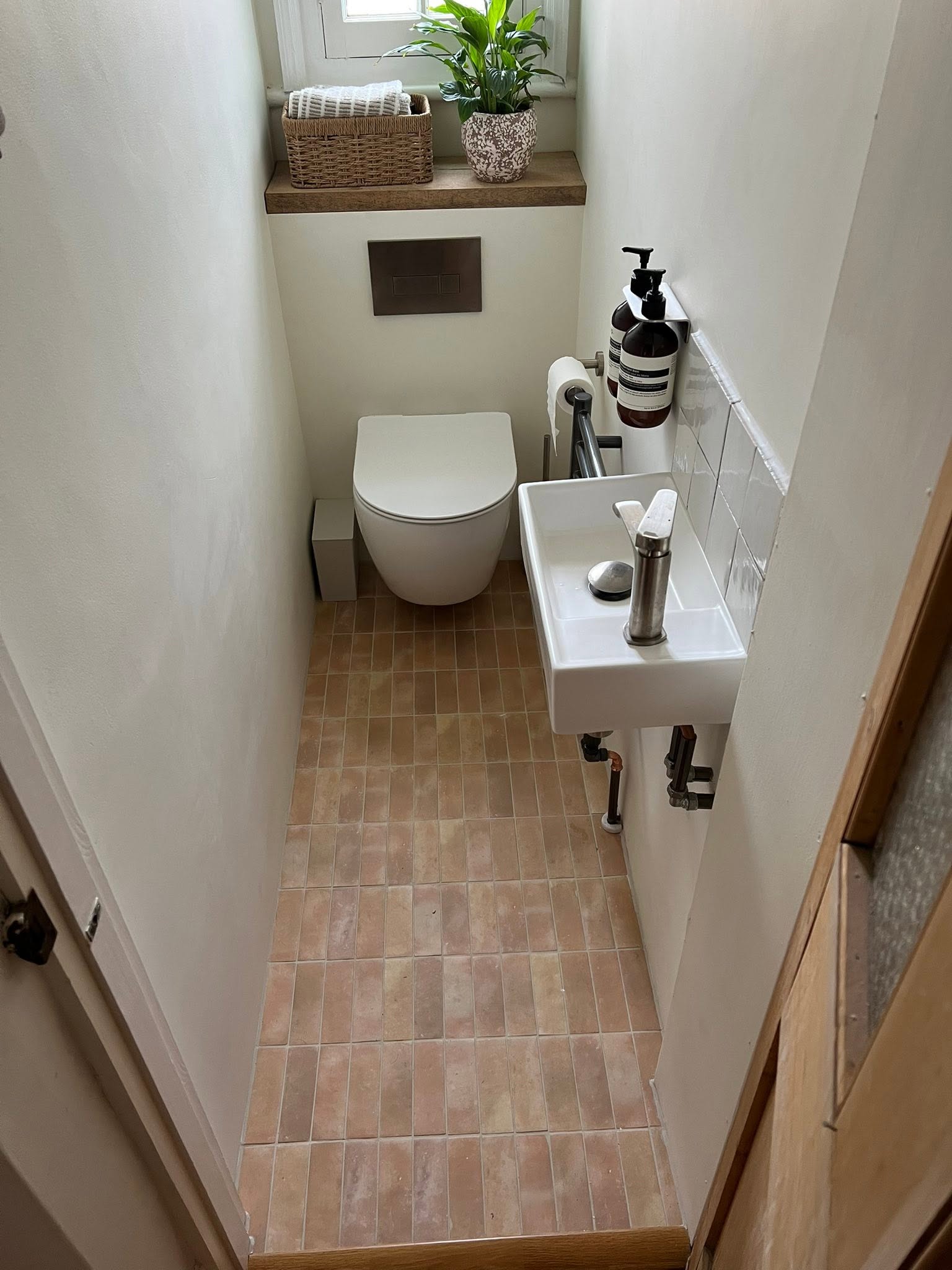 Neatly tiled small bathroom with wall-hung toilet and compact sink