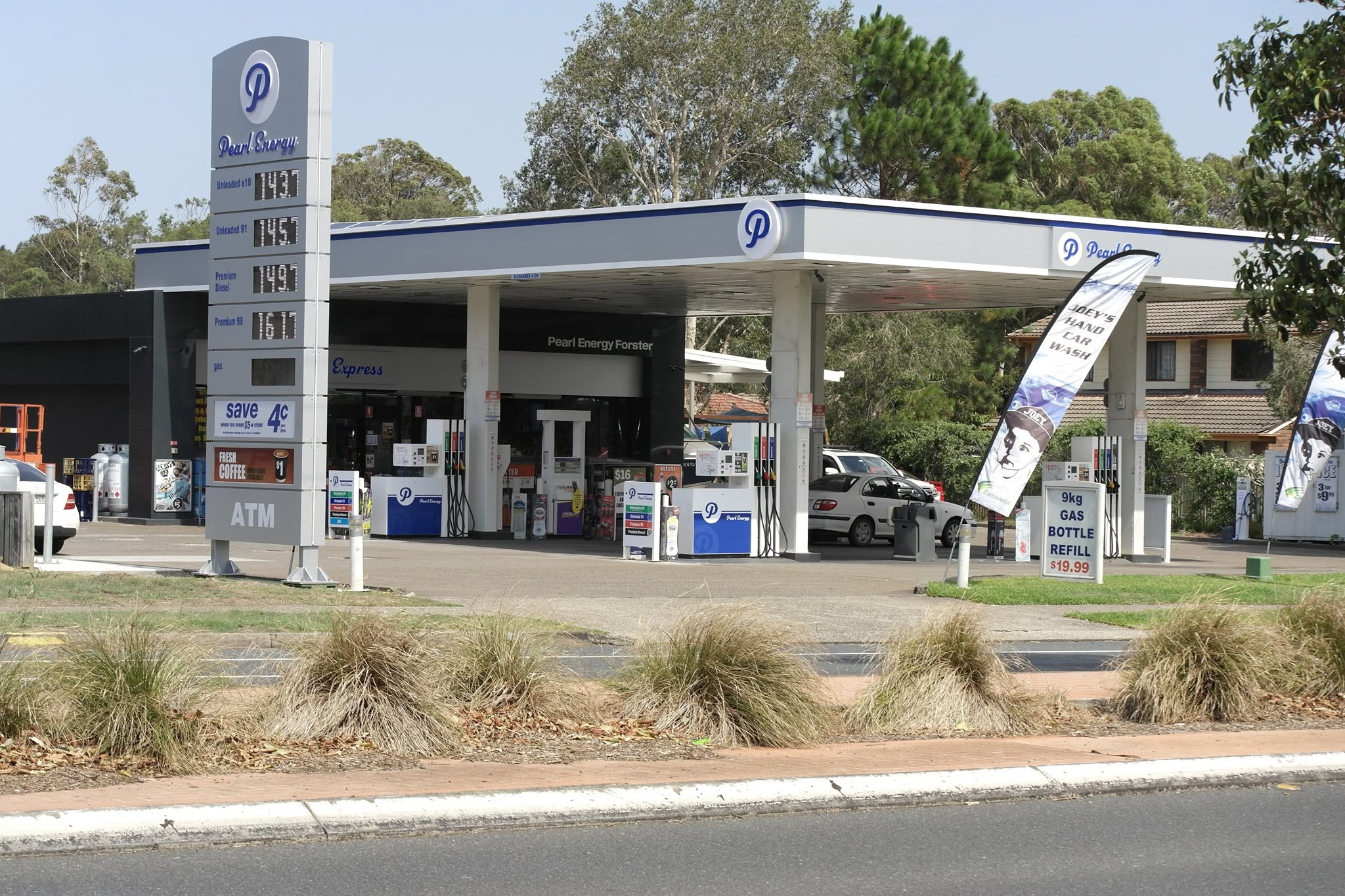Pearl Energy service station forecourt during daytime showing fuel pumps and signage
