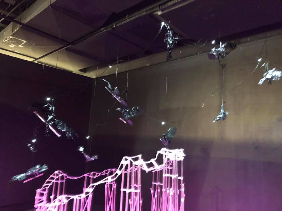 Purple hanging installation with glowing pink light structure — abstract art